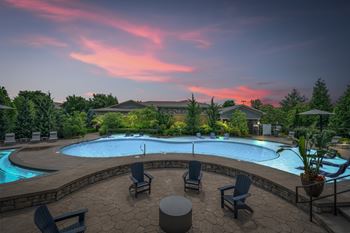 A beautiful outdoor swimming pool area with lounge chairs and a hot tub.